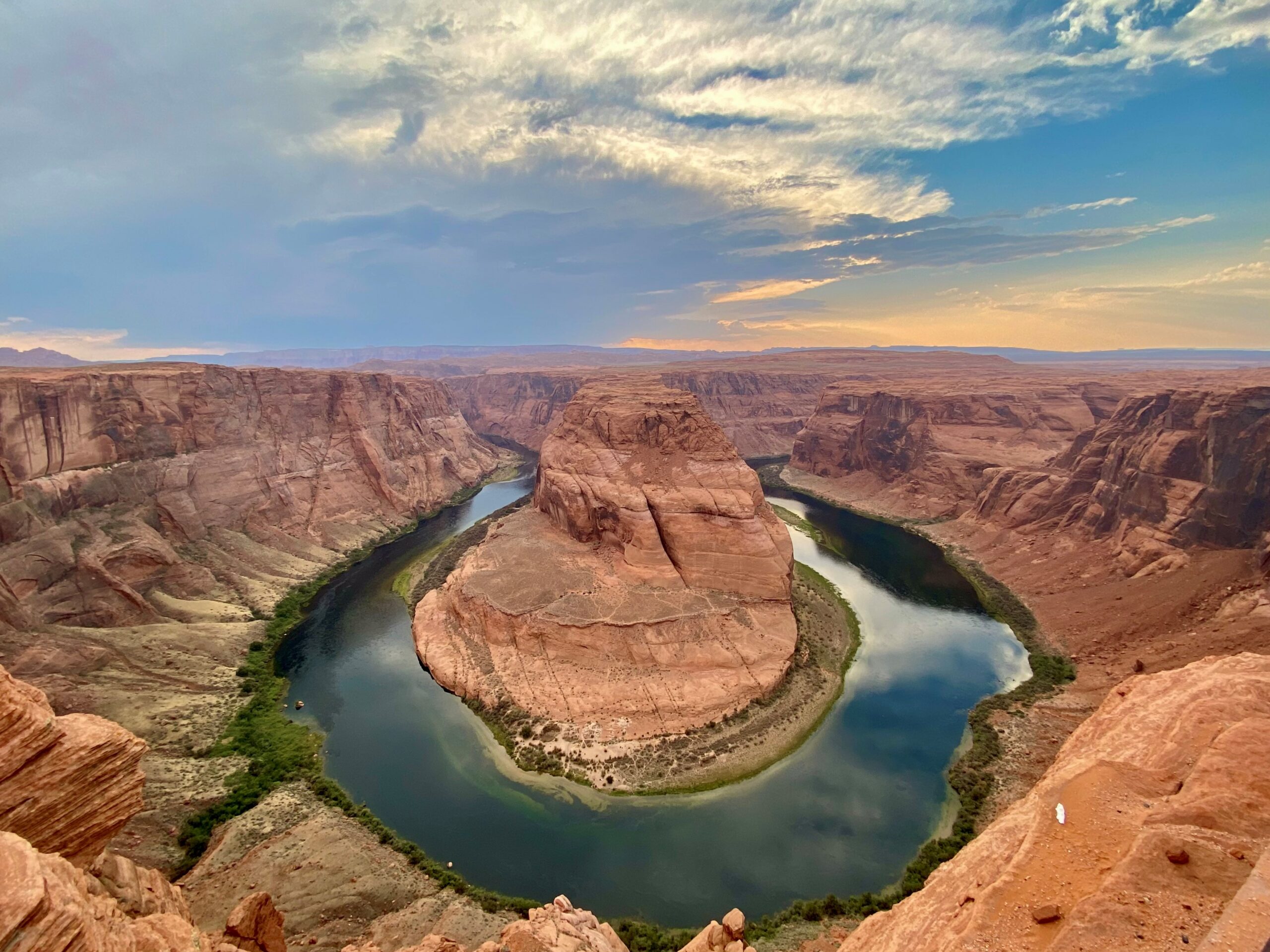 Aerial view of the Colorado River curving through red canyon walls at sunset, forming a dramatic horseshoe bend.