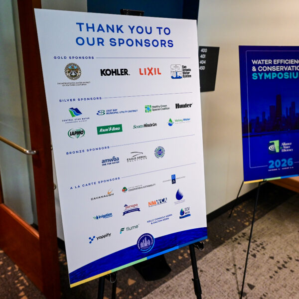 Sponsor display board with multiple logos and the heading 'Thank you to our sponsors' in blue text near a blue event poster in the background.